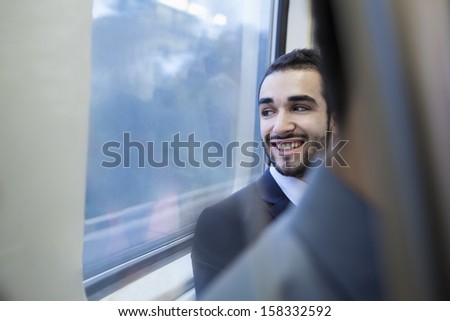 Young businessman smiling and looking out the window of subway