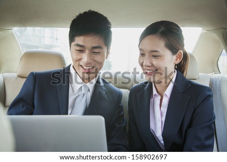 Business people working in back seat of car