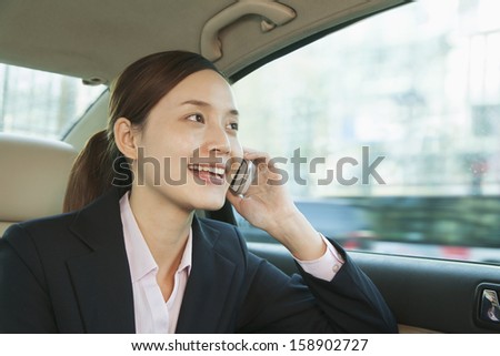 Businesswoman in back seat of car on the phone