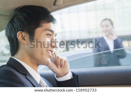 Businessman in back seat of car on the phone