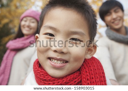 Close up of young boy with family in park in autumn