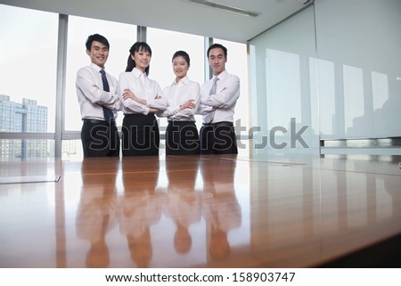 Four young business people standing by conference table