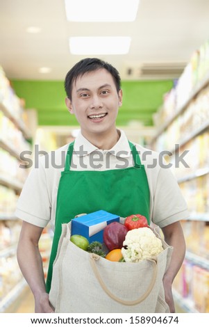 Young man holding bag with fruits and vegetables