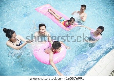 Family and friends playing in water at the pool with inflatable tubes