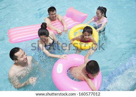 Family and friends playing in water at the pool with inflatable tubes