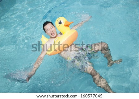 Man wearing yellow duck inflatable tube and playing in pool