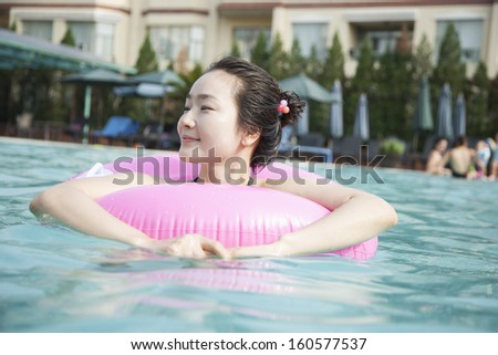 Smiling young women in the pool with inflatable tube