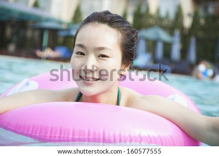 Portrait of smiling young women in pool with inflatable tube