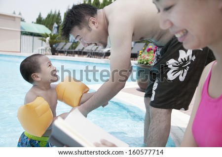 Young happy family relaxing by pool on vacation