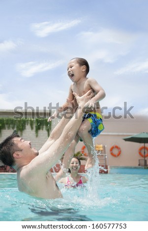 Smiling father lifting his son out of the water