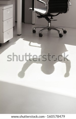 Shadow of business person on floor with arms raised cheering