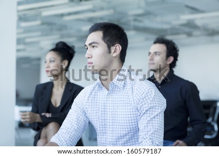 Three serious business people sitting in business meeting