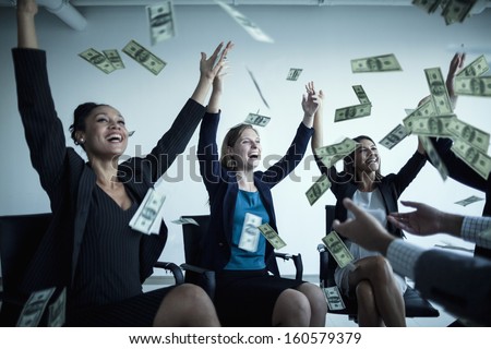 Business people with arms raised throwing money in air