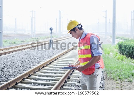 Railroad worker in protective work wear checking the railroad tracks