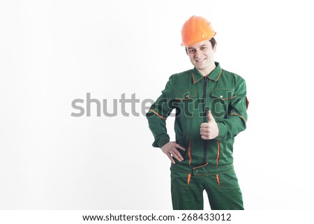 Smiling construction worker in working order and a helmet holding a thumb up and shows, that all will be well!