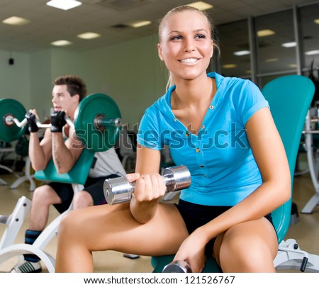 A young women lifting free weights with a confident smile
