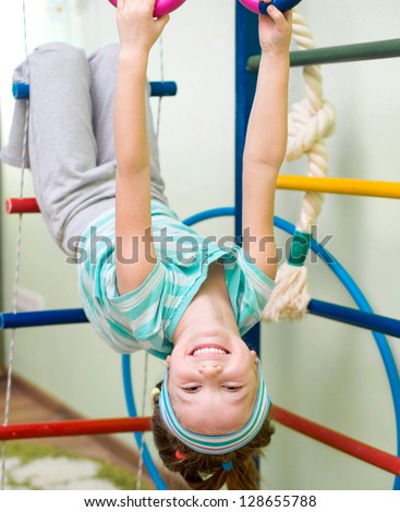 six year old girl playing at gymnastic rings