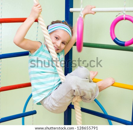 happy little girl doing sports gymnastics at home gym
