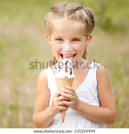 Beautiful little girl eats ice-cream in the summer Beautiful little girl eats ice-cream in the summer