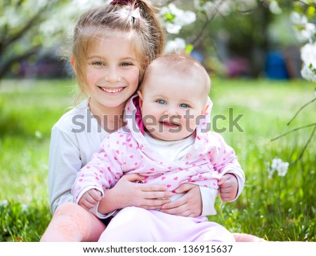 two lovely sisters in a meadow on a sunny summer day