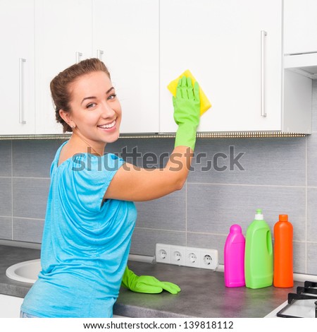 smiling cute woman cleans the kitchen at her home