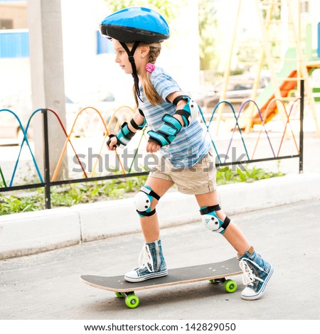 little  girl with a helmet riding on skateboard in the park