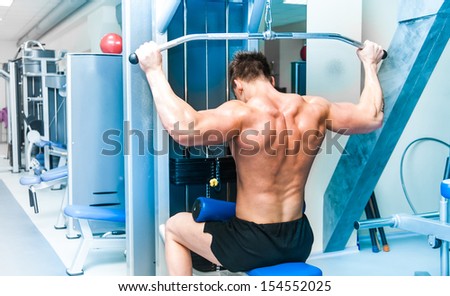strong athletically built sportsman doing back exercises in a gym