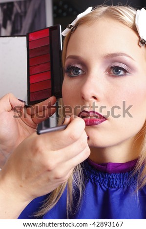 Makeup artist tracing red lipstick on the lips of a girl
