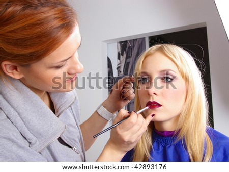 Makeup artist tracing red lipstick on the lips of a girl