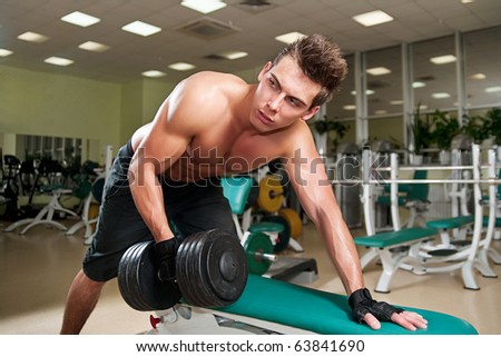 Muscular man working his biceps with heavy dumbbells