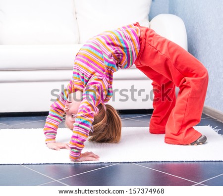 happy  little girl playing sports at home in front of a white sofa