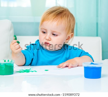 cute baby    draw finger paints at home in bright living room