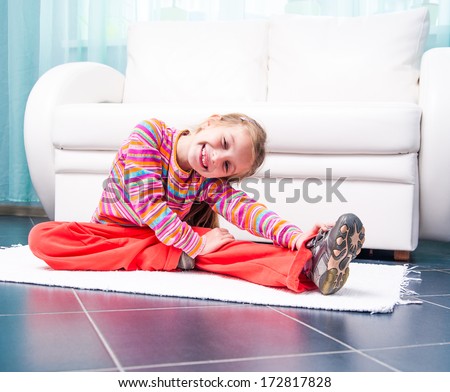 happy pretty little girl playing sports at home in front of a white sofa