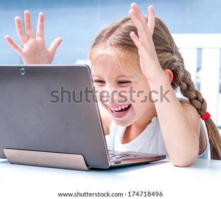 happy little girl with her computer at home at the table