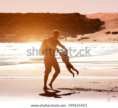Dad playing with baby daughter on the beach at sunset Dad playing with baby daughter on the beach at sunset
