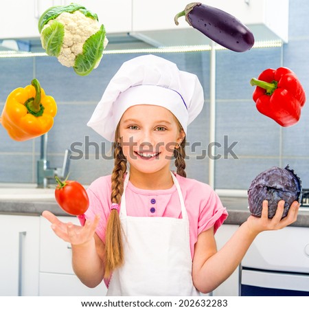 smiling little girl juggle vegetables home in the kitchen