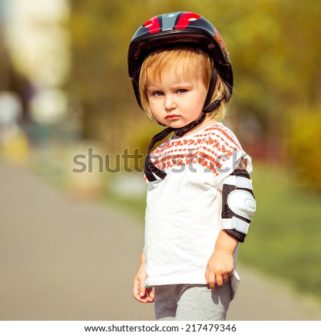 two year old pretty girl in  a helmet on the street close-up