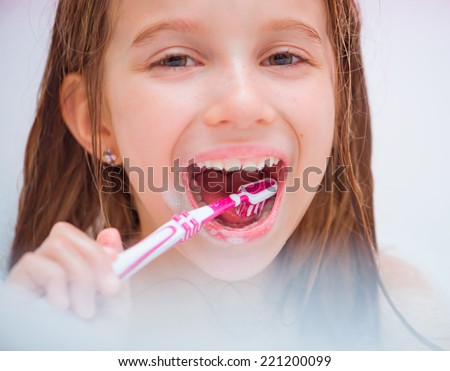 Little happy  girl brushing teeth in bath