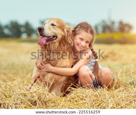 happy little girl with her dog golden retriever in rural areas in summer