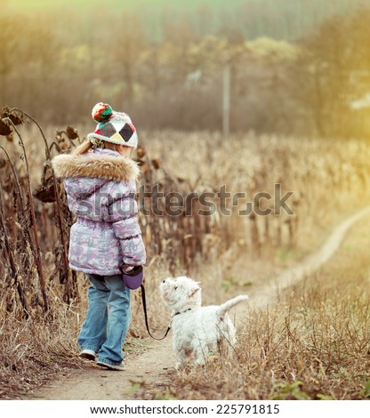 happy cute girl with her dog breed White Terrier walking in a field