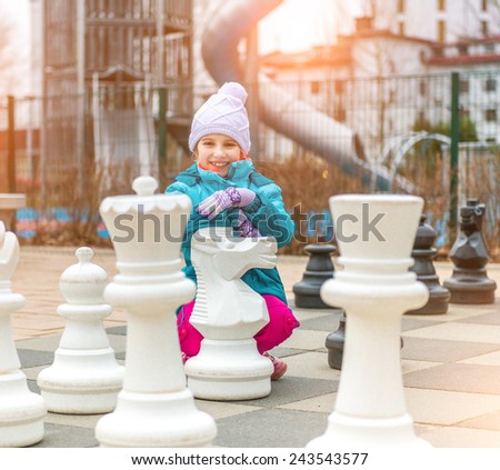 Chess game with giant chess piece. Girl playing strategic outdoor game