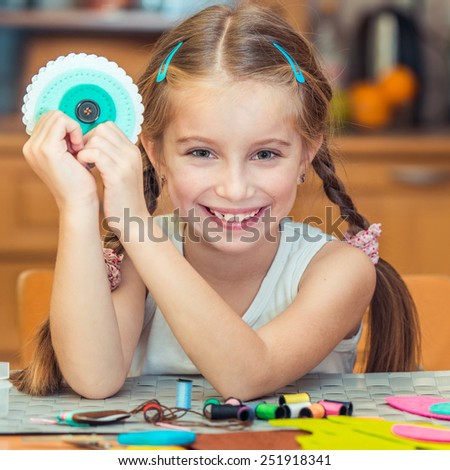 happy cute little girl shows  materials for needlework