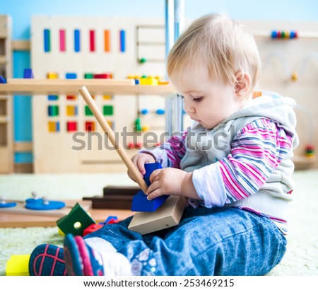little girl in the classroom early development plays with numerous bright toys