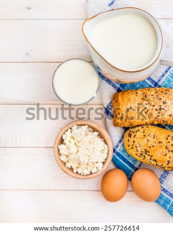 Breakfast of cheese, milk, bread and eggs on a light wooden background