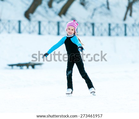 happy little girl in thermal suits skating in winter outdoors