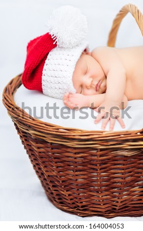 Cute newborn baby wearing Santa Claus hat sleeping in basket, Christmas, New Year