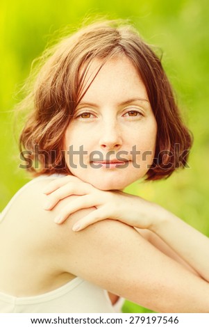 Outdoor portrait of lovely freckled young woman who hugging herself and looking at camera. Orange and yellow natural toning