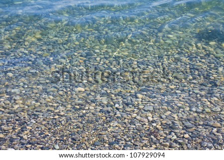 Sea landscape - little stones on shore inside water.
