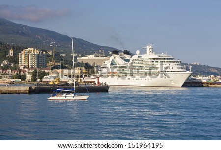 Big cruise liner stands in port of town Yalta, resort in region Crimea on Black sea in Ukraine.