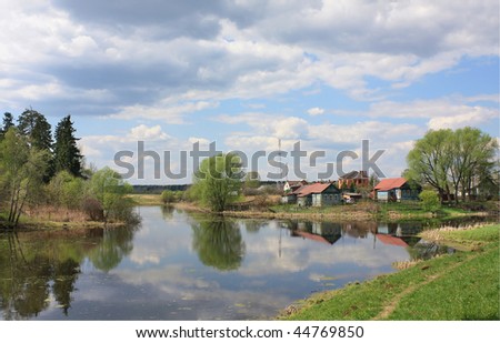 Summer landscape: river, wooden houses. Recorded in Russia.